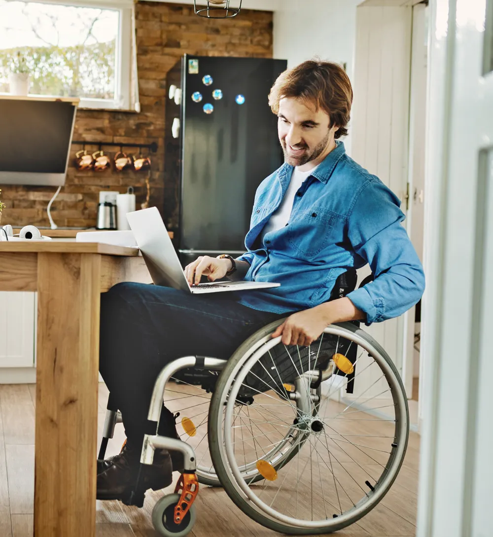 NDIS participant managing finances on laptop in accessible SDA home Gold Coast